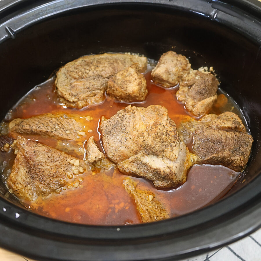 Cooked pork roast in a slow cooker with cooking liquid