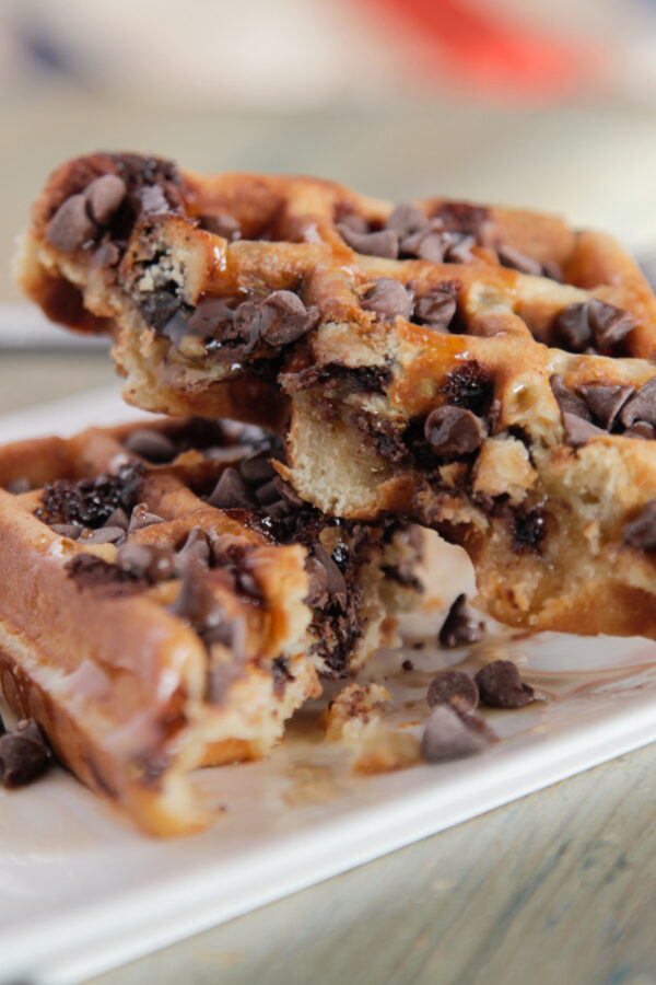 A homemade chocolate chip waffle cut in half on a plate