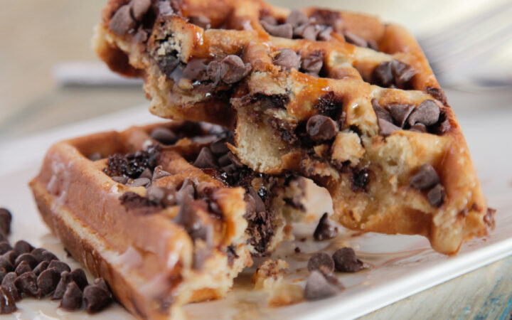 A homemade chocolate chip waffle cut in half on a plate