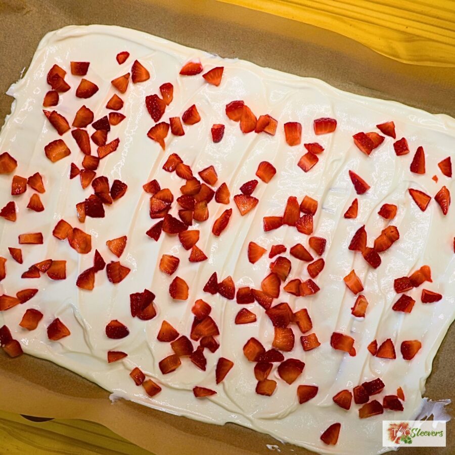 Overhead image of Greek yogurt spread on parchment paper with chopped strawberries on top