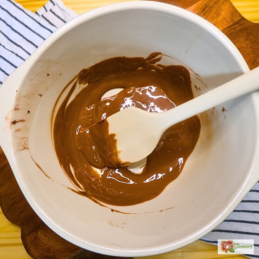 Overhead image of chocolate melted in a mixing bowl with a silicon spatula in it