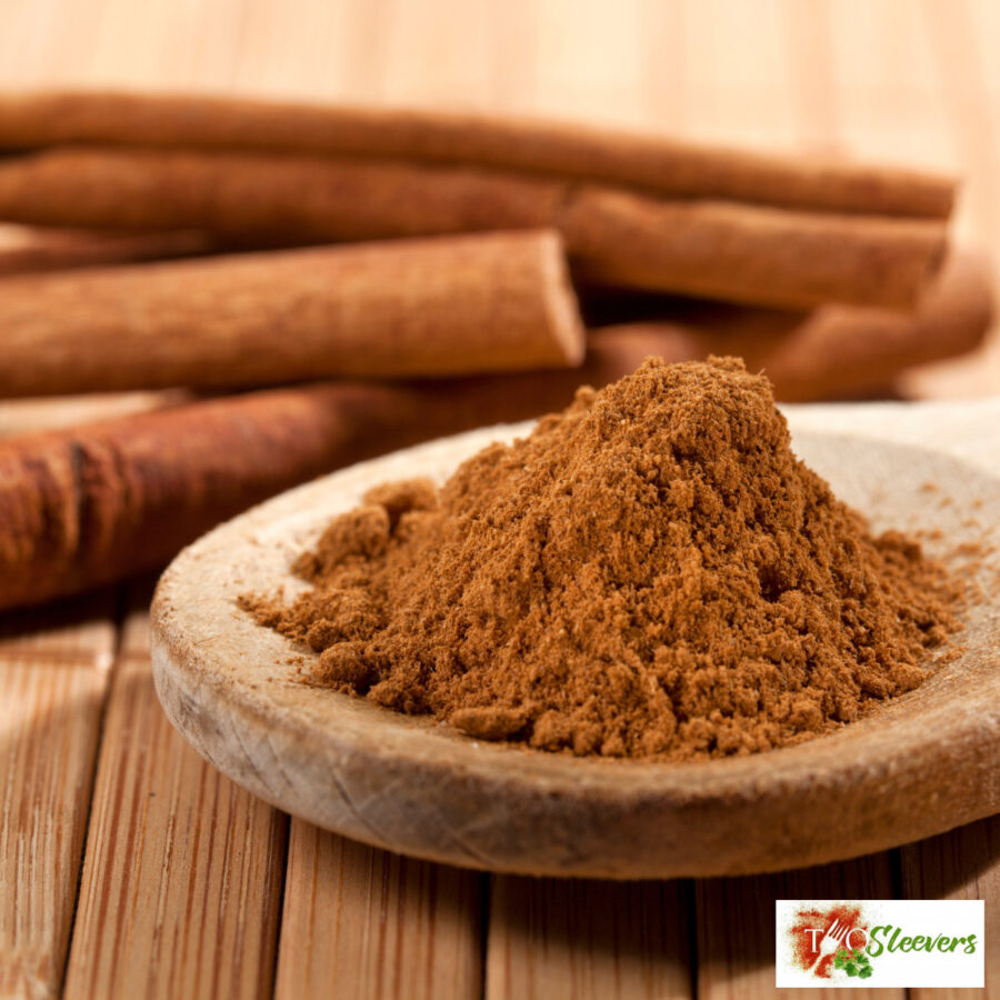 Ground Cinnamon on a wooden spoon with cinnamon sticks next to it