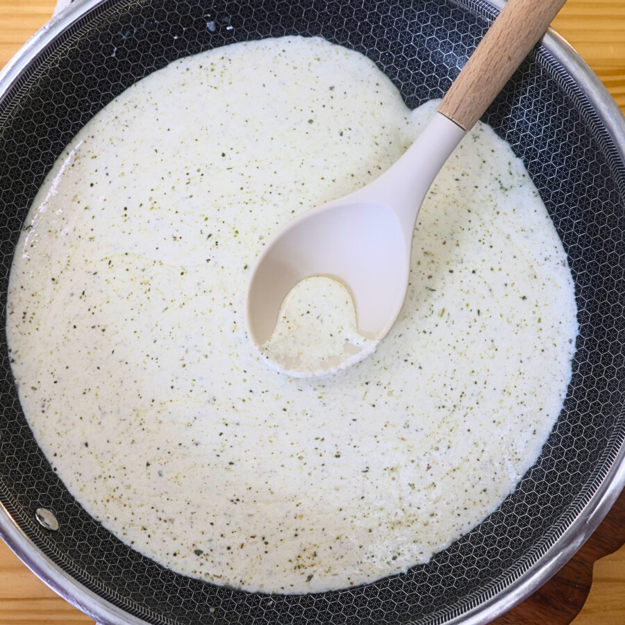 Overhead image of cottage cheese alfredo sauce in a pan with a large spoon