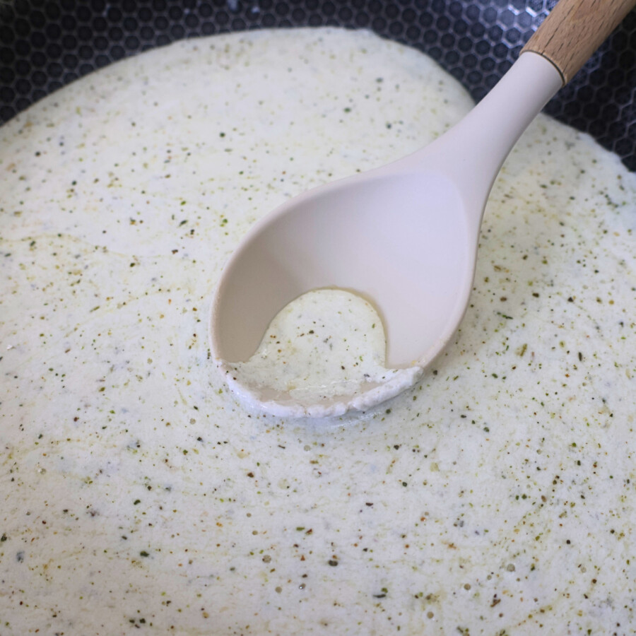 Cottage Cheese Alfredo Sauce in a pan being scooped with a large spoon