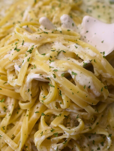 Fetuccini alfredo with cottage cheese alfredo sauce being served with a pasta server