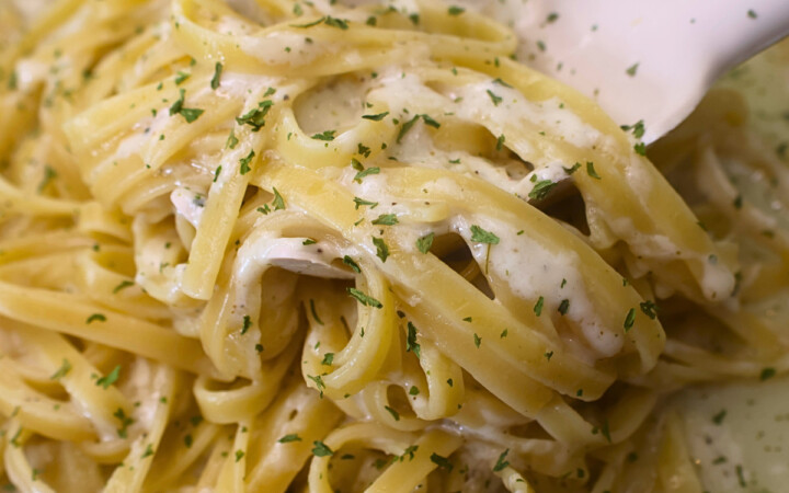 Fetuccini alfredo with cottage cheese alfredo sauce being served with a pasta server