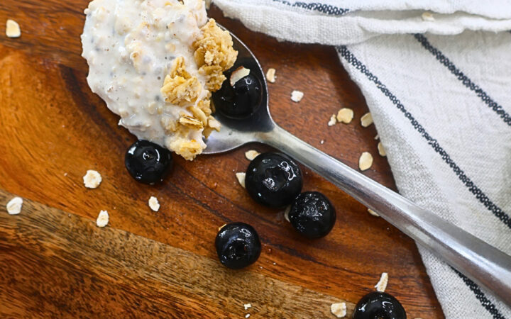 Close up image of cottage cheese overnight oats on a spoon with granola and blueberries