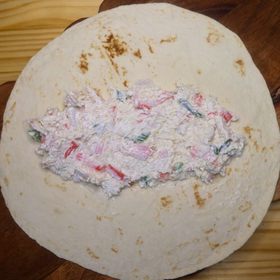 A flour tortilla with crab rangoon filling in the middle of it
