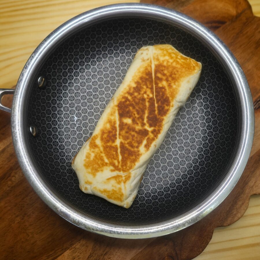 A Crab rangoon burrito being toasted in a skillet