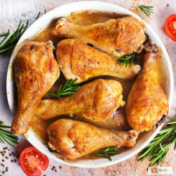 overhead image of crispy baked chicken legs in a white dish with herbs