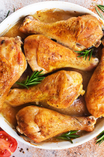 overhead image of crispy baked chicken legs in a white dish with herbs