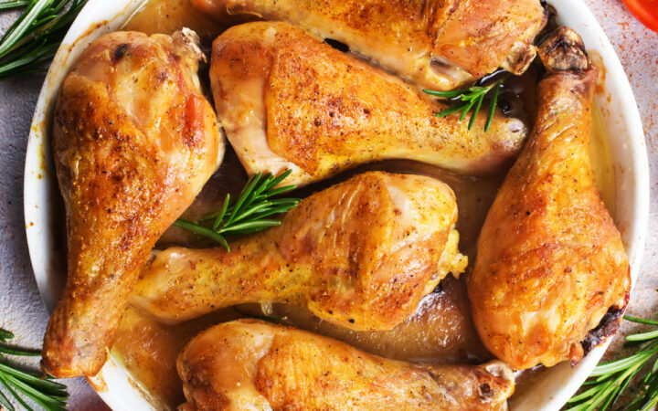 overhead image of crispy baked chicken legs in a white dish with herbs