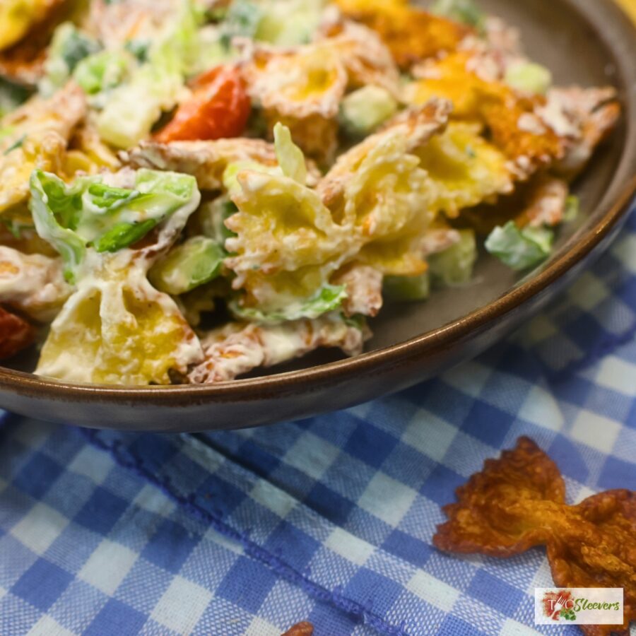 close up image of viral crispy pasta salad in a bowl with blue gingham under it