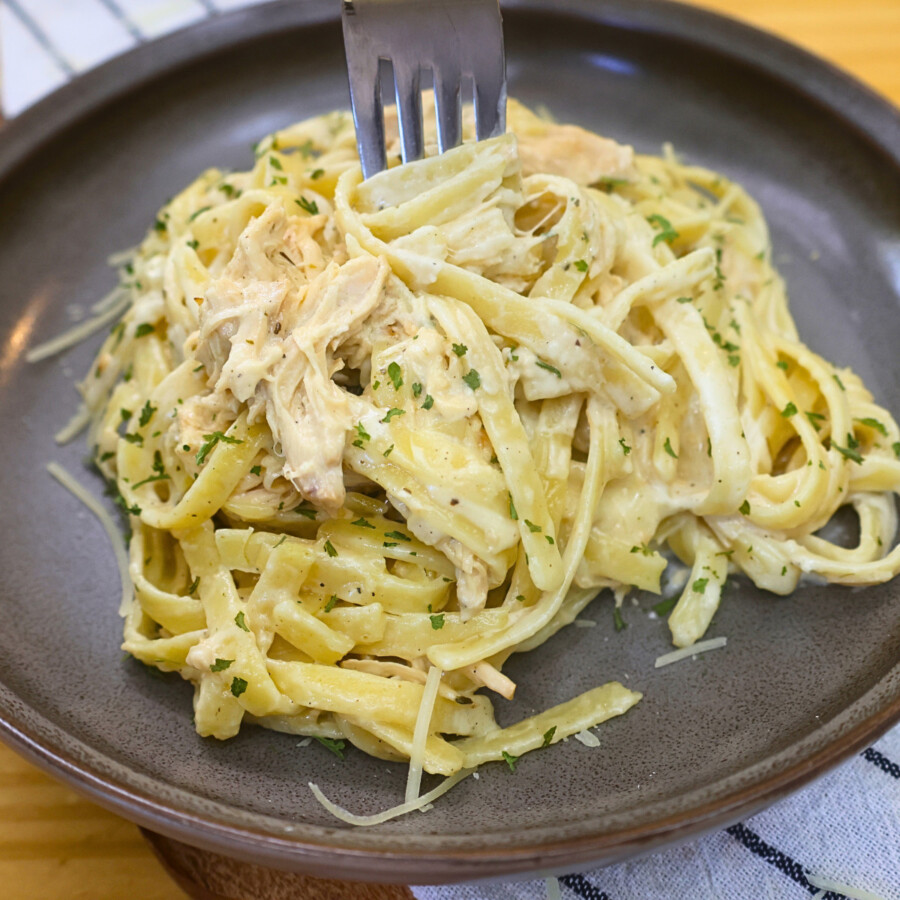 Crockpot Chicken Alfredo on a plate being eaten with a fork