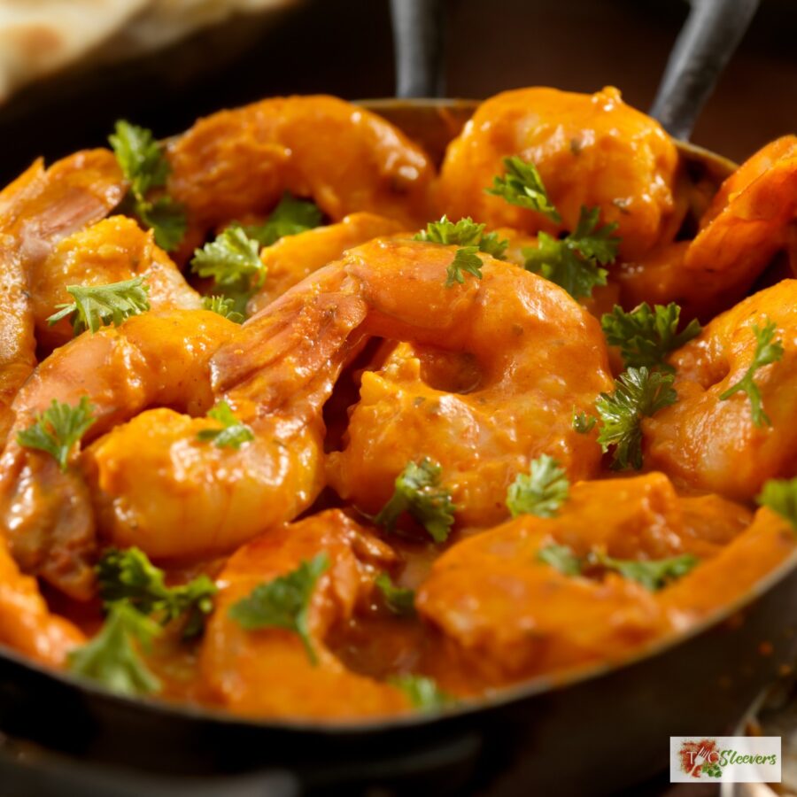 Close up image of curry shrimp in a pan with cilantro garnish