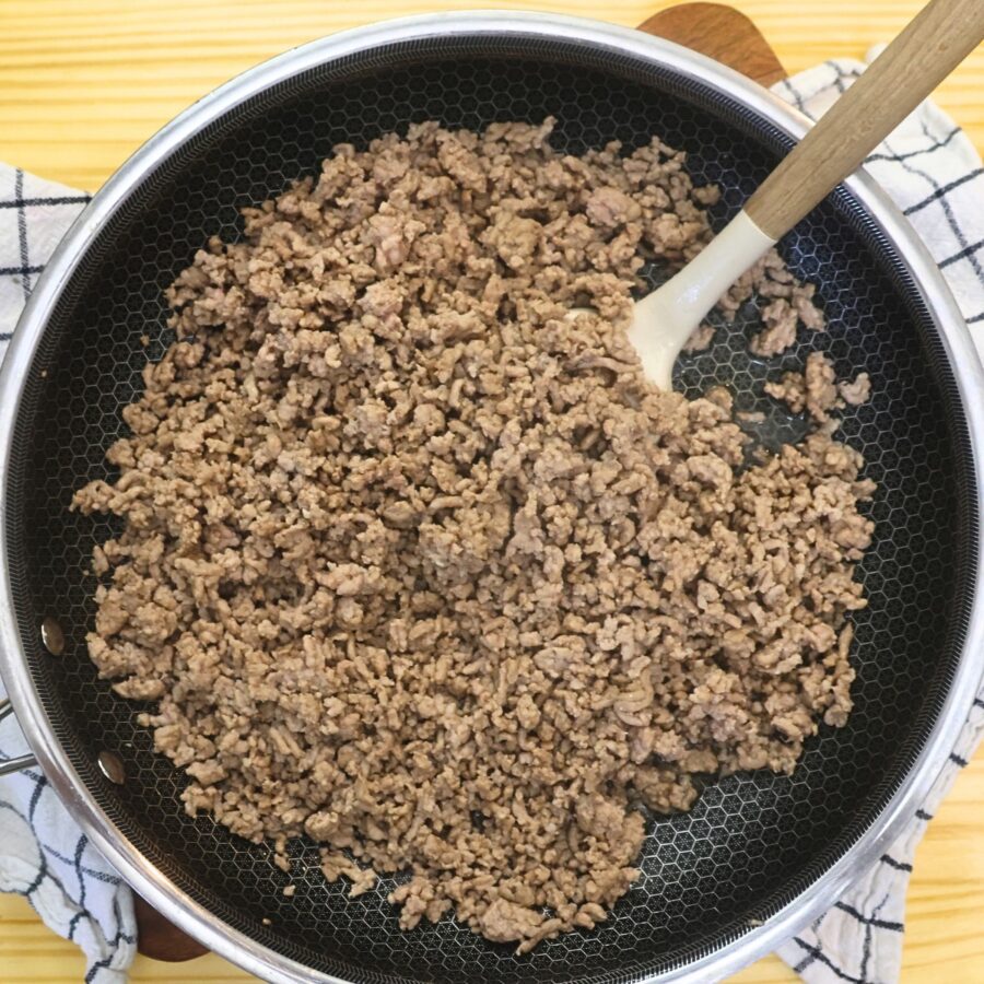Cooked ground pork in a skillet with a spatula