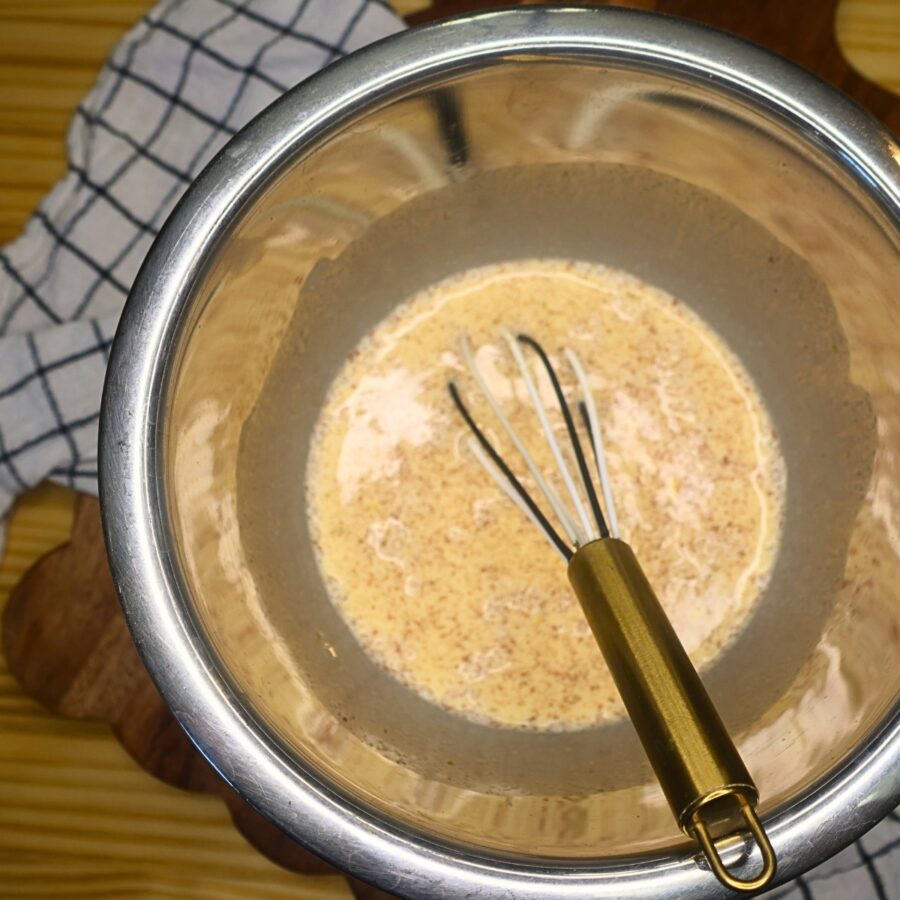 Custard in a metal bowl with a whisk