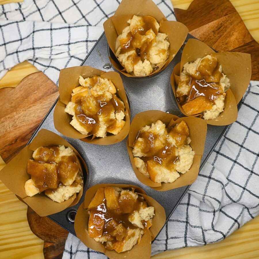 Unbaked french toast muffins with sugary topping poured over the top