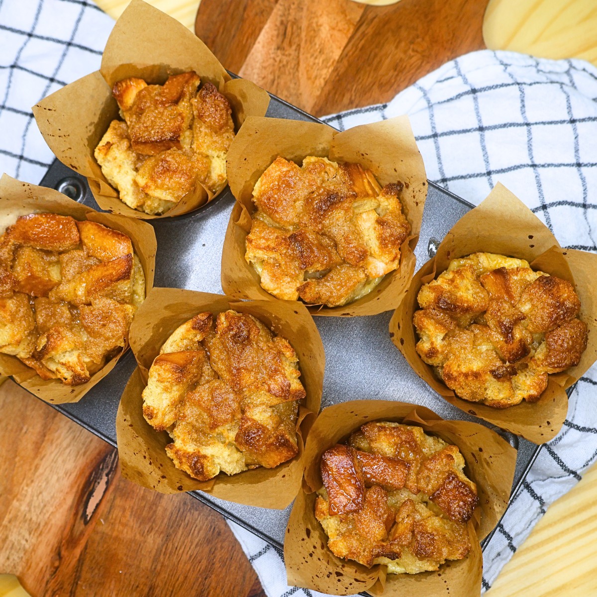 Six French Toast Muffins in a baking tin on a rustic backdrop