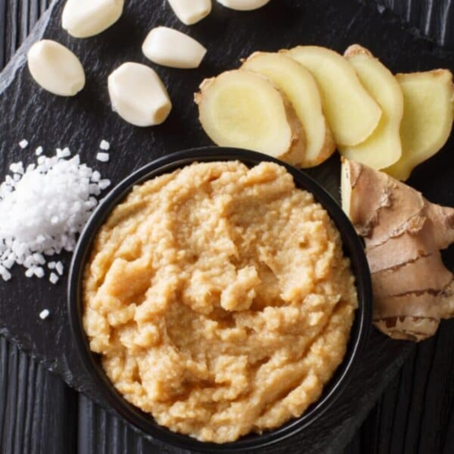 Ginger garlic paste in a bowl with whole and sliced ginger next to it