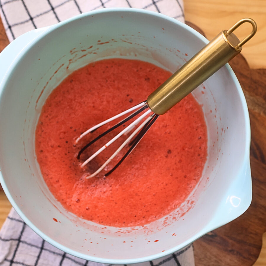 Overhead image of a bowl of sugar free jello being dissolved in hot water with a whisk in it