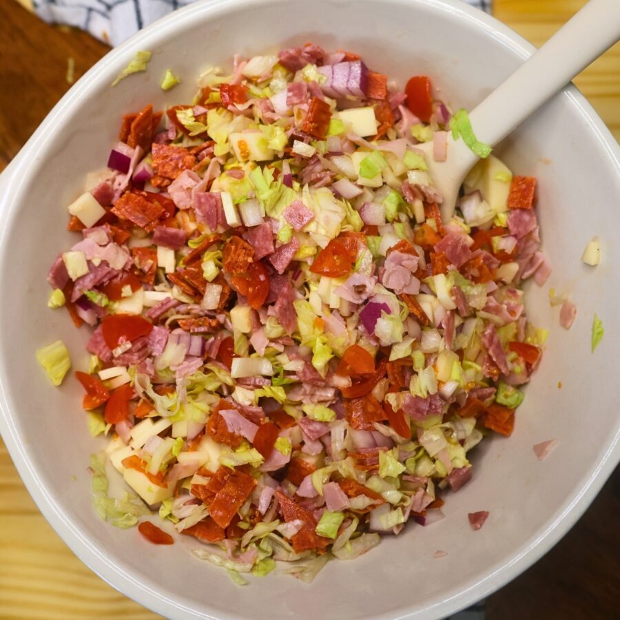 Overhead image of chopped meat, cheese, and vegetables in a mixing bowl with a spatula