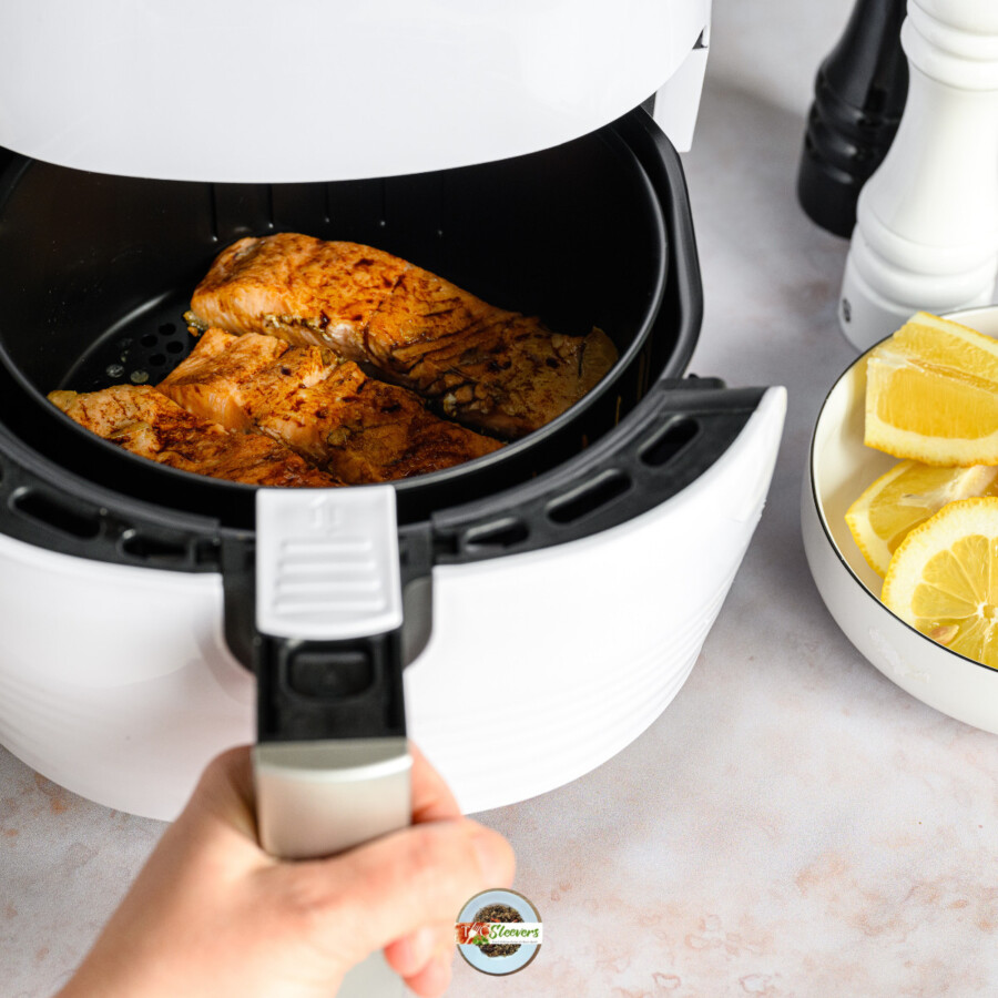 An air fryer being opened with food being cooked inside