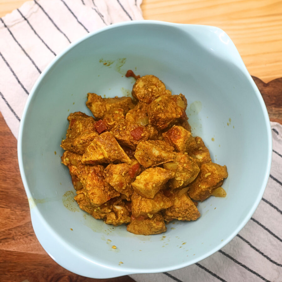 Chicken removed from the sauce in a blue bowl