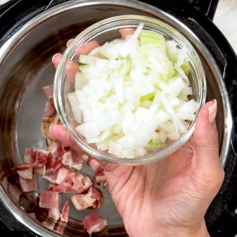 Diced onion being added to an Instant Pot with diced uncooked bacon