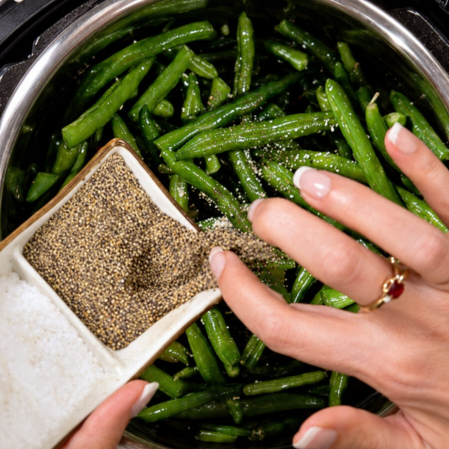 Green beans in an Instant Pot with salt and pepper being added