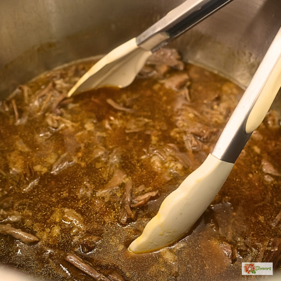Instant Pot Korean Beef with thickened sauce in an Instant Pot liner with tongs