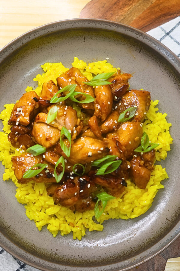 Overhead image of air fryer Korean BBQ chicken over a bed of yellow rice on a plate