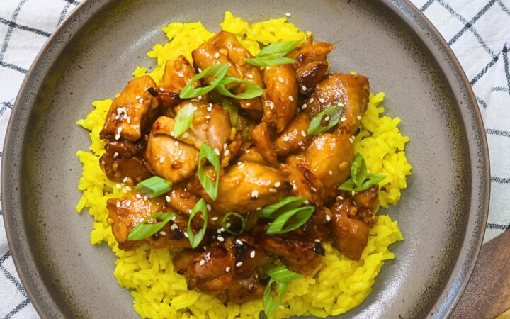 Overhead image of air fryer Korean BBQ chicken over a bed of yellow rice on a plate