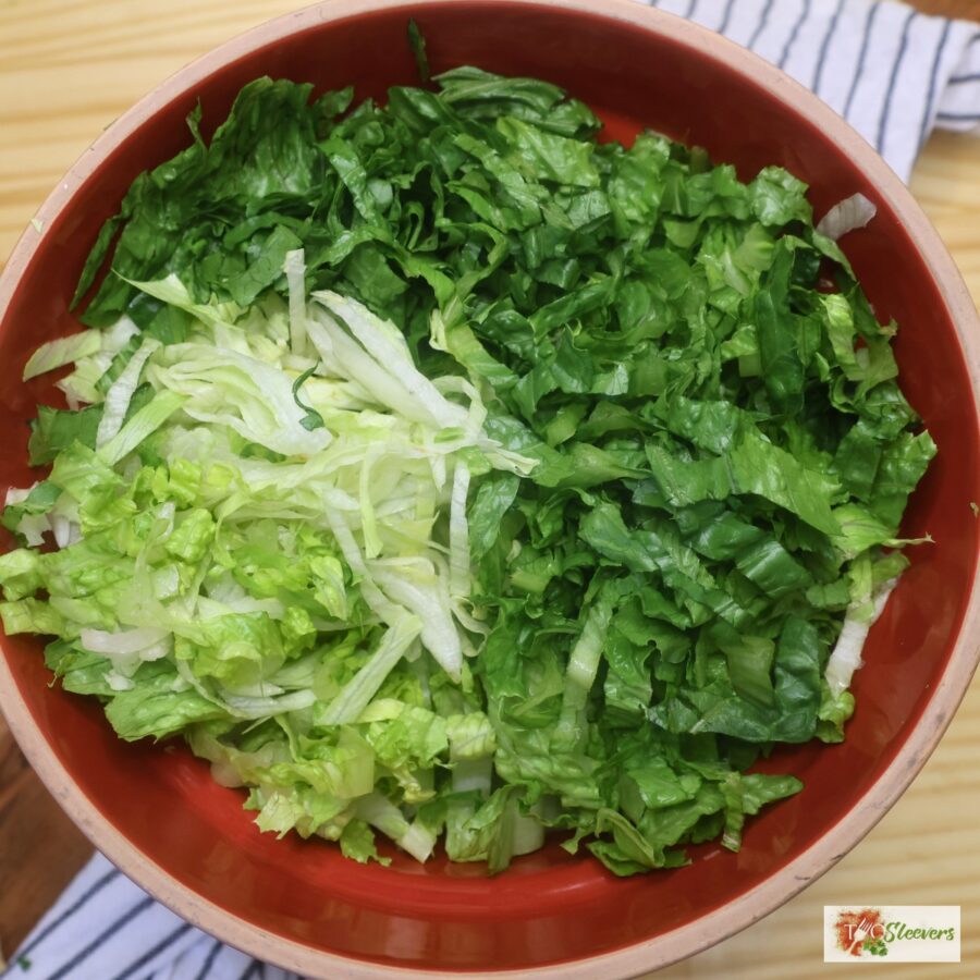 Overhead image of iceberg and romaine lettuce shredded in a bowl
