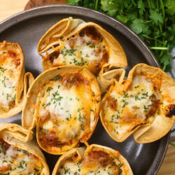 Close up image of Low Carb Lasagna cups on a plate with greenery in the background