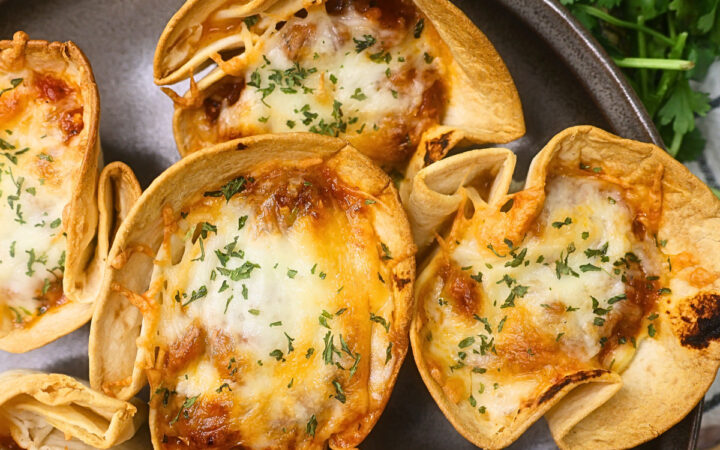 Close up image of Low Carb Lasagna cups on a plate with greenery in the background