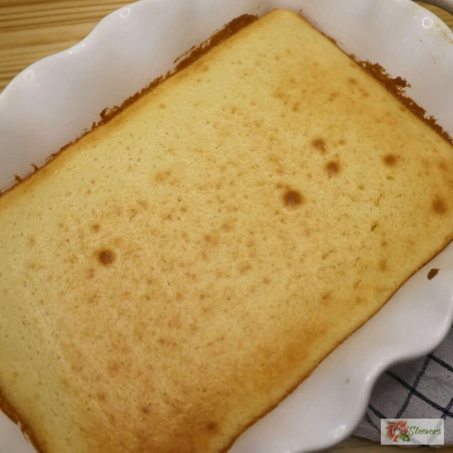 A white baking pan with a vanilla cake baked inside