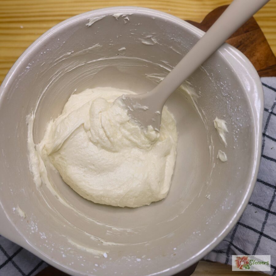 Buttercream frosting in a mixing bowl with a silicone spatula