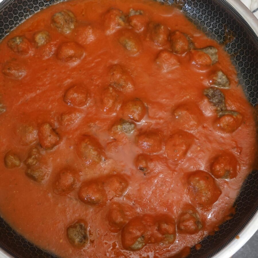 Cooked mini meatballs in a skillet with marinara sauce