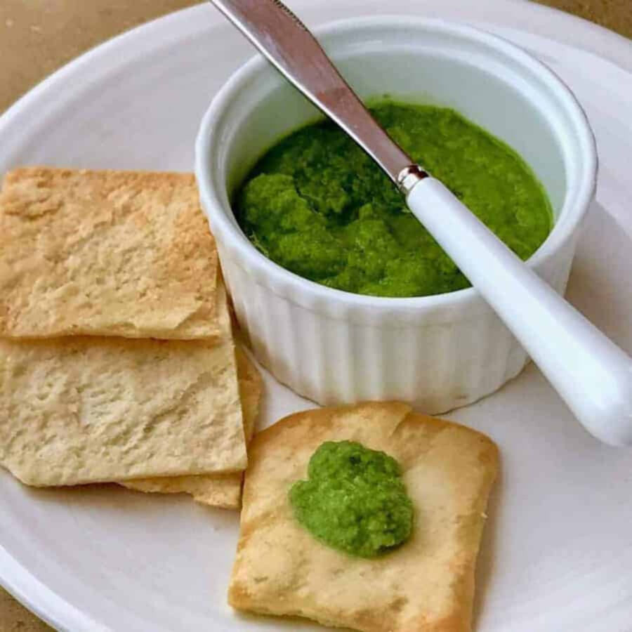 Mint chutney in a white ramekin with a knife to spread it on flatbread