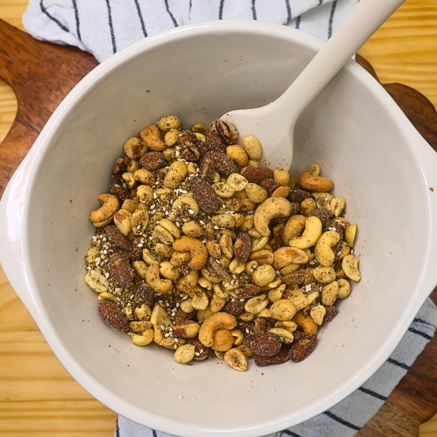 Mixed nuts and ground flaxseed in a mixing bowl with a silicone spatula