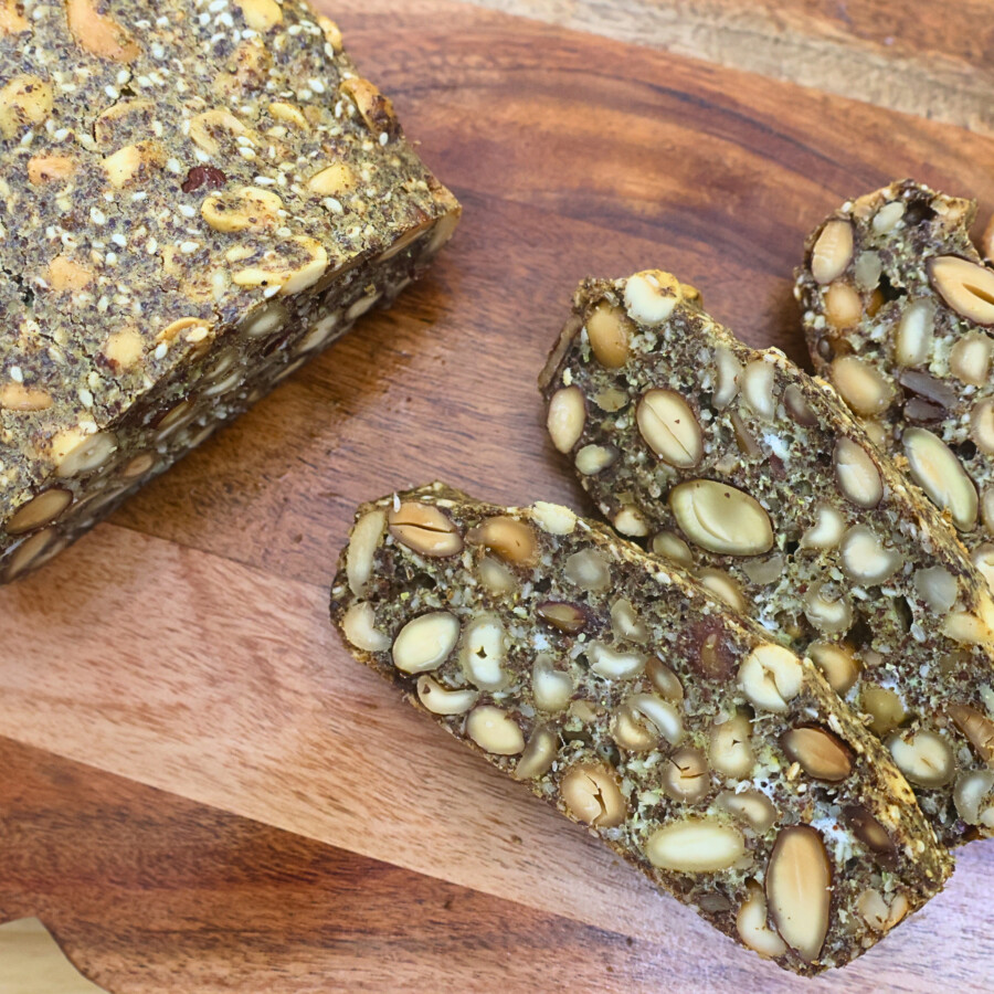 A loaf of nut and seed bread with slices cut off of it