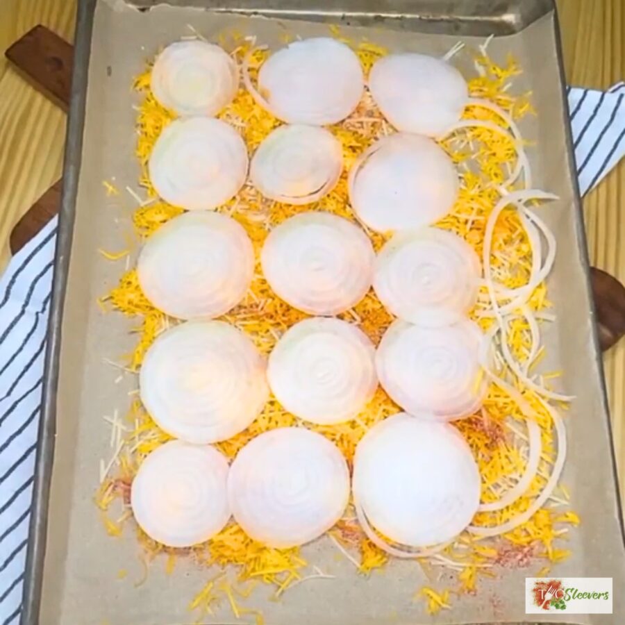 sliced onion over the top of seasoned shredded cheese on parchment paper