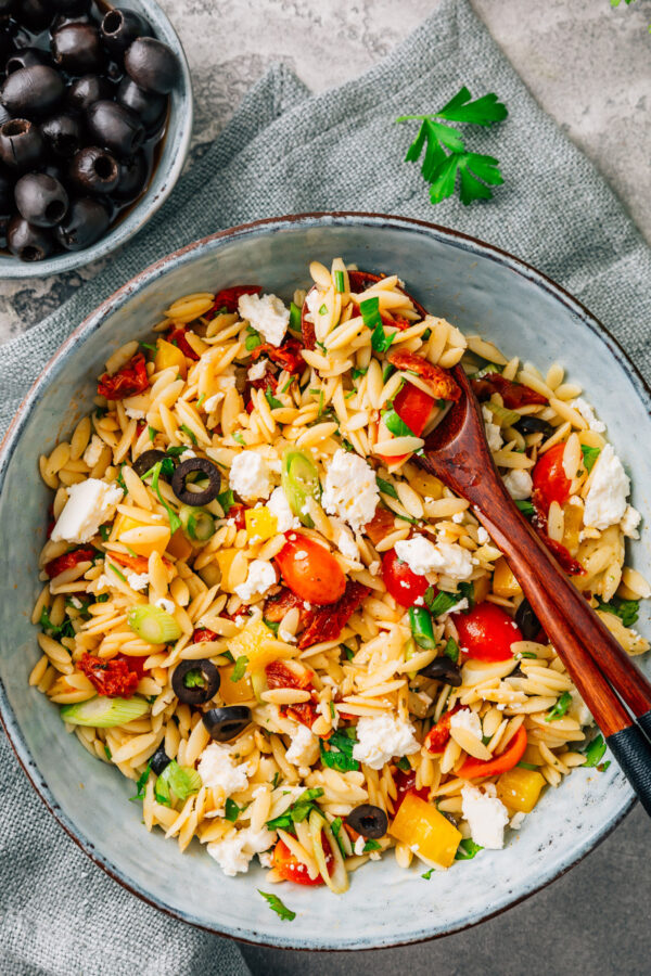 Overhead image of Orzo Salad in a bowl with serving spoons
