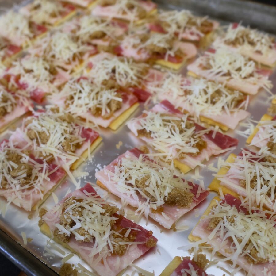 Crackers with bacon topped with brown sugar and parmesan cheese