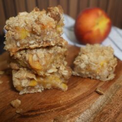 Close up image of peach Crumble Bars stacked on a wooden serving board