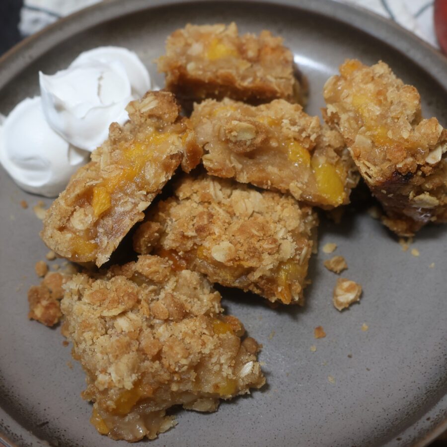 Peach Crumble bars on a plate wth whipped topping