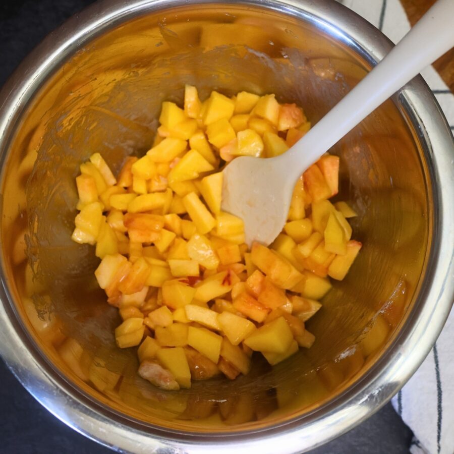 Peach crumble bar filling being mixed in a metal bowl with a silicone spatula
