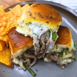Close up image of Philly Cheesesteak Sliders on a plate with chips
