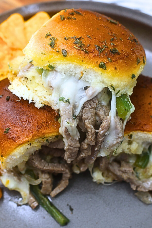 Close up image of Philly Cheesesteak Sliders on a plate with chips